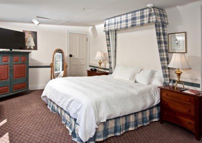 Room with curtains behind bedframe, flatscreen TV and antiques